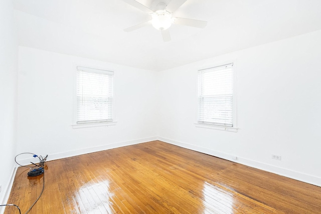 unfurnished room featuring a wealth of natural light, wood-type flooring, and baseboards