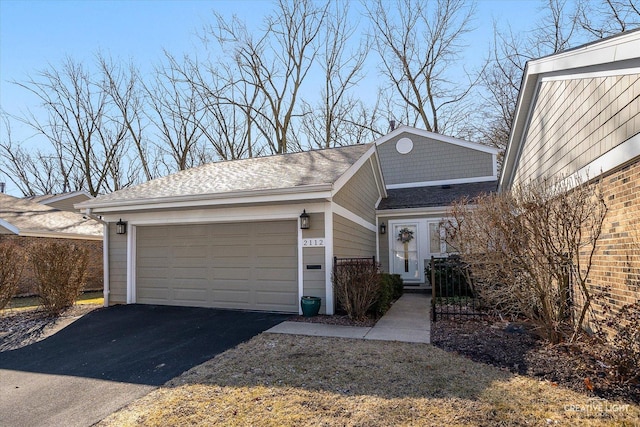 exterior space with aphalt driveway and roof with shingles