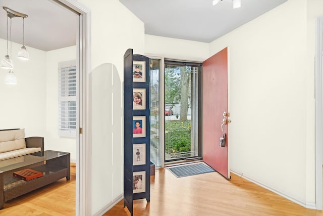 entryway featuring arched walkways, light wood finished floors, and a wealth of natural light