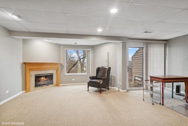 living area featuring carpet, a drop ceiling, baseboards, and a premium fireplace