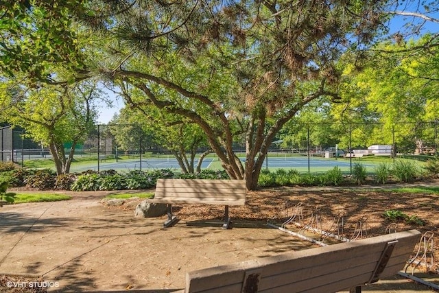 surrounding community with a tennis court and fence