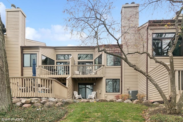 back of property featuring a deck, a yard, central AC unit, and a chimney