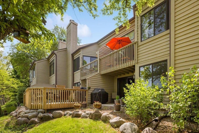 rear view of property with a deck, a chimney, and a balcony