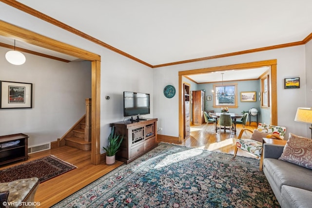 living area with stairway, wood finished floors, baseboards, and ornamental molding