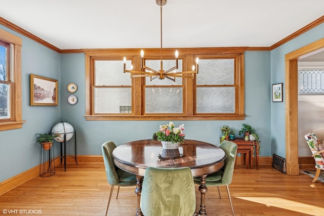 dining room with a notable chandelier, crown molding, baseboards, and wood finished floors