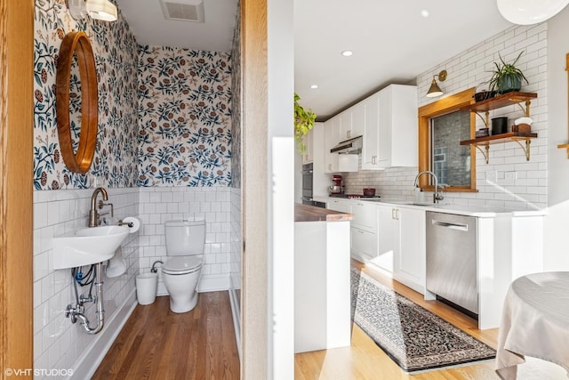 full bath featuring visible vents, toilet, wood finished floors, wainscoting, and wallpapered walls