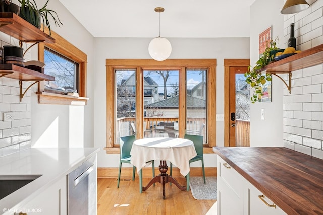 dining space featuring a healthy amount of sunlight, light wood-style flooring, and baseboards