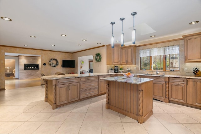 kitchen featuring light tile patterned floors, ornamental molding, open floor plan, light stone countertops, and a sink