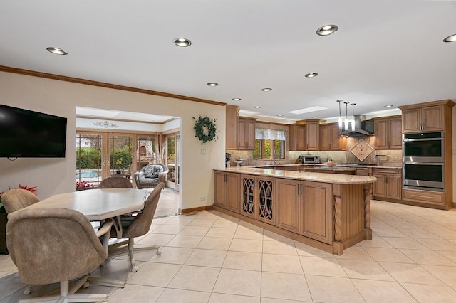 kitchen featuring wall chimney exhaust hood, tasteful backsplash, and brown cabinetry