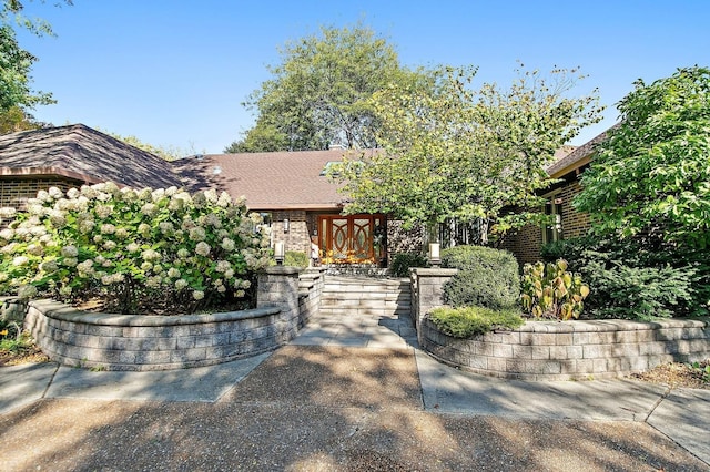 view of front of house with a shingled roof and brick siding