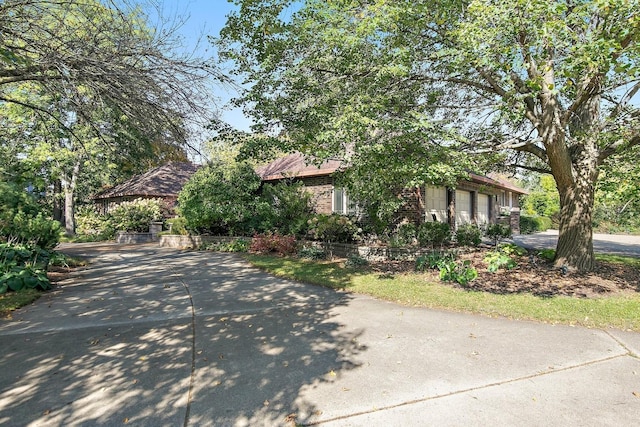 view of front of home with a garage, brick siding, and driveway