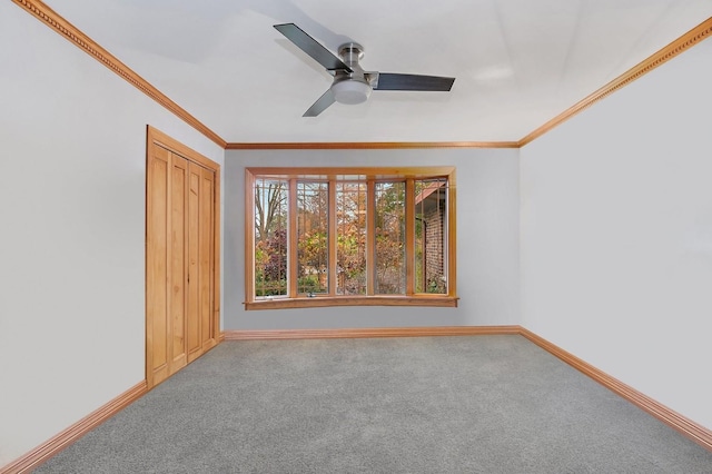 empty room featuring ornamental molding, ceiling fan, carpet floors, and baseboards