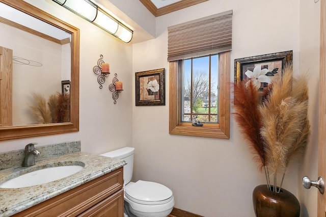 half bathroom with vanity, toilet, and crown molding