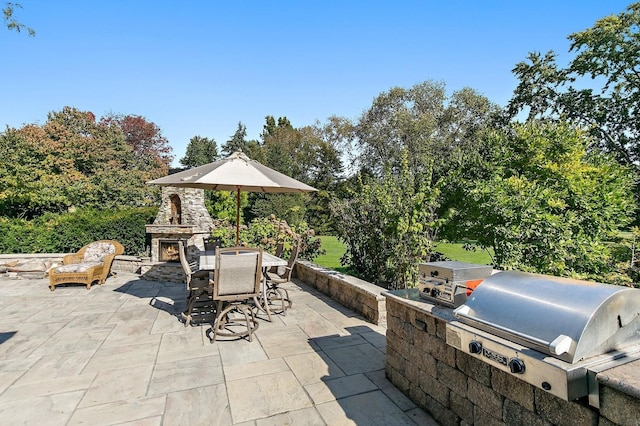 view of patio featuring exterior kitchen, an outdoor stone fireplace, a grill, and outdoor dining area