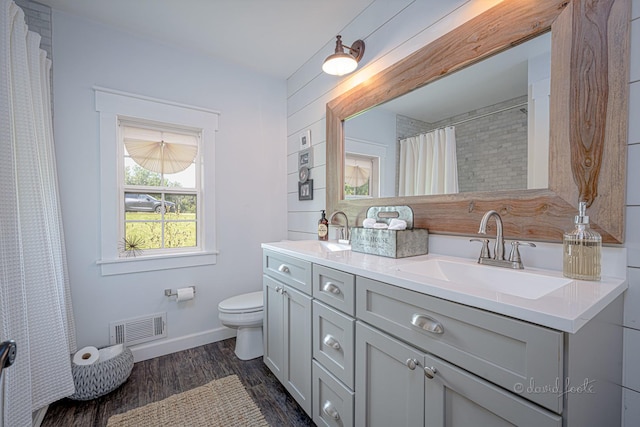 full bath with visible vents, toilet, vanity, wood finished floors, and baseboards