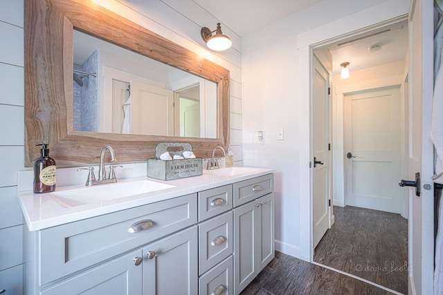 full bathroom with double vanity, wood finished floors, and a sink