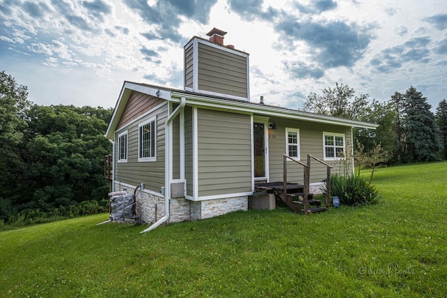 back of property featuring a chimney and a lawn