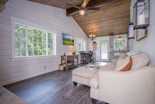 living room featuring lofted ceiling with beams, wood ceiling, dark wood-type flooring, wood walls, and ceiling fan with notable chandelier