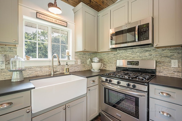 kitchen with dark countertops, appliances with stainless steel finishes, backsplash, and a sink