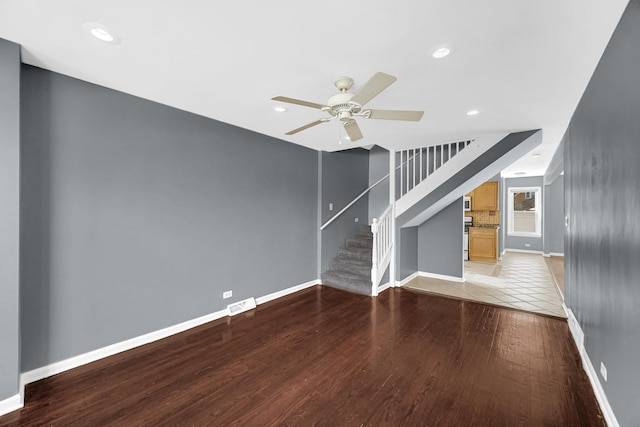 unfurnished living room featuring light wood finished floors, visible vents, baseboards, a ceiling fan, and stairway