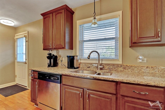 kitchen with a sink, light stone countertops, light wood-style flooring, and dishwasher