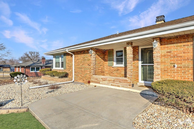 view of front of property with a porch, brick siding, and a chimney