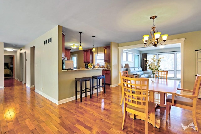 dining room with dark wood-style floors, baseboards, visible vents, and a notable chandelier