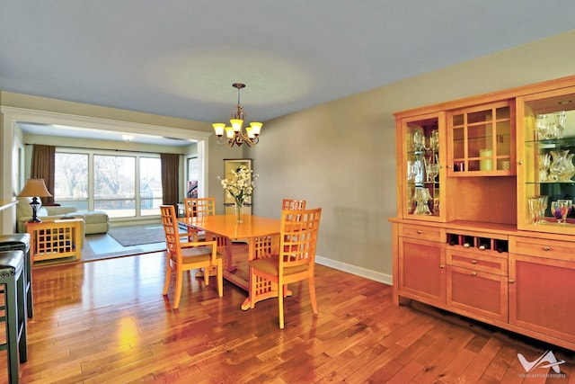 dining area with wood-type flooring, a chandelier, and baseboards