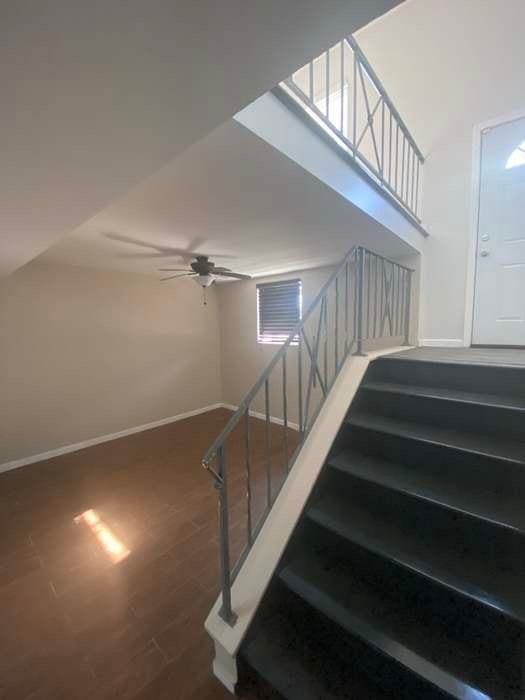 stairway featuring a ceiling fan, baseboards, and wood finished floors