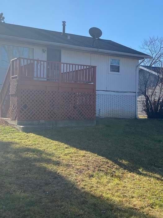 rear view of house with a lawn and a wooden deck