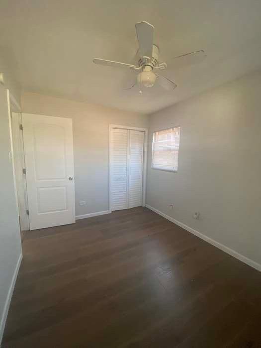 unfurnished bedroom featuring a closet, wood finished floors, a ceiling fan, and baseboards