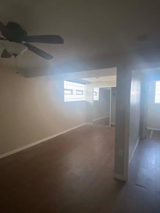 unfurnished room with ceiling fan, plenty of natural light, wood finished floors, and baseboards