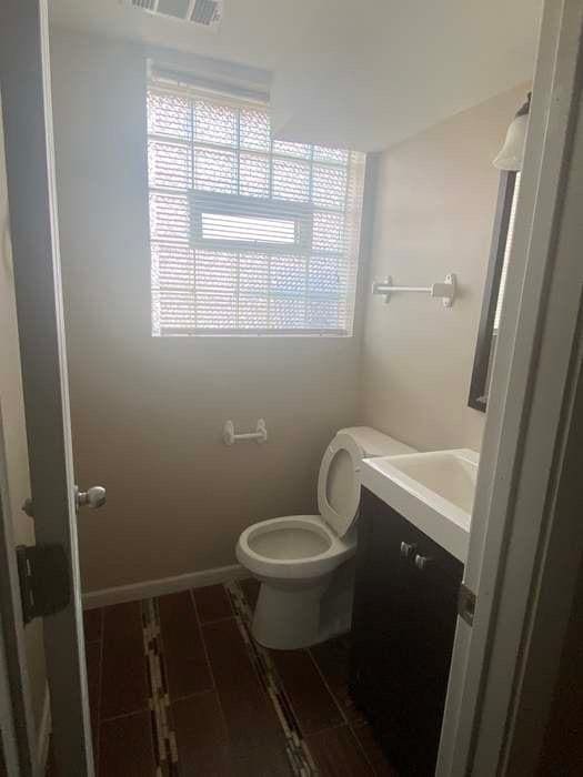 bathroom featuring visible vents, toilet, vanity, wood finished floors, and baseboards