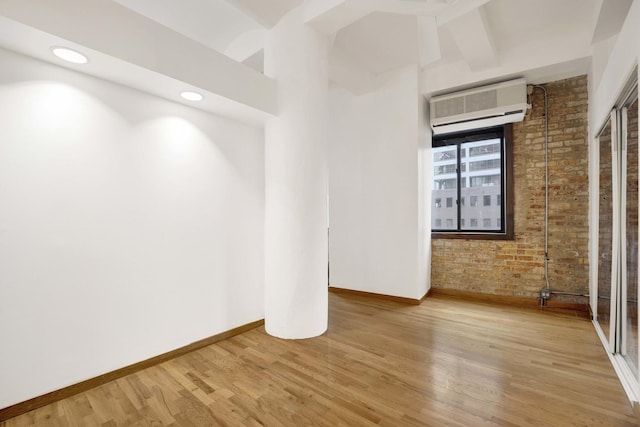 spare room featuring recessed lighting, brick wall, baseboards, light wood-style floors, and an AC wall unit