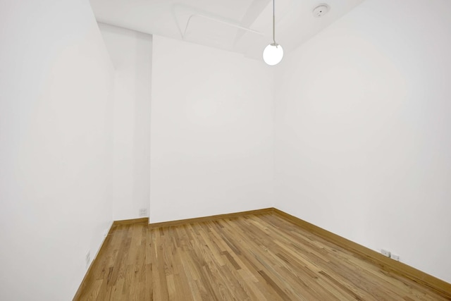 spare room with baseboards and light wood-style floors