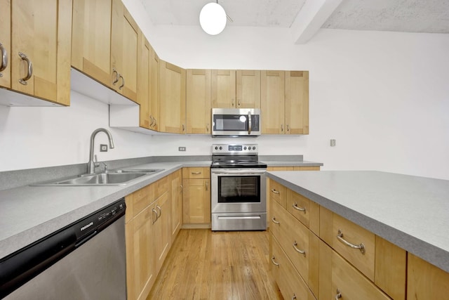 kitchen with stainless steel appliances, light brown cabinetry, and a sink