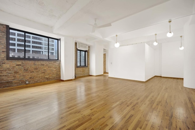 unfurnished room with baseboards, brick wall, a ceiling fan, and wood finished floors