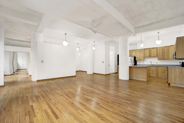 kitchen featuring decorative light fixtures, light wood-style flooring, freestanding refrigerator, open floor plan, and a sink