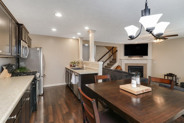 dining space featuring a tiled fireplace, a ceiling fan, dark wood-style flooring, ornate columns, and recessed lighting