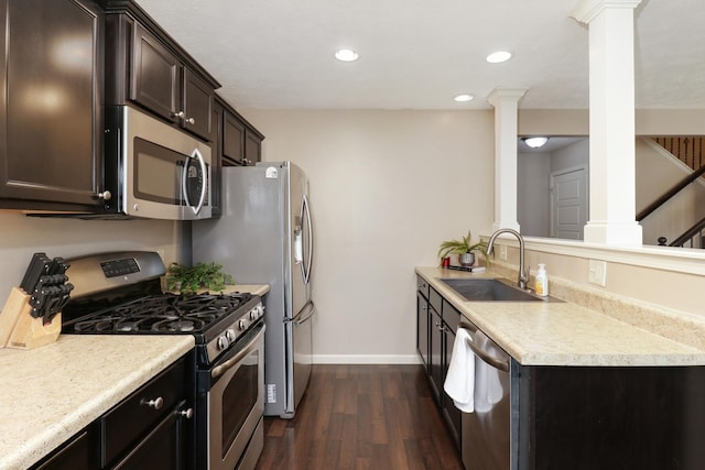 kitchen with decorative columns, light countertops, appliances with stainless steel finishes, a sink, and dark brown cabinetry