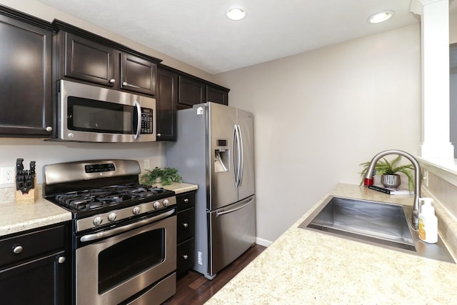 kitchen featuring dark wood-style flooring, light countertops, appliances with stainless steel finishes, a sink, and dark brown cabinetry