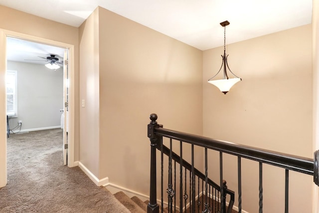 corridor featuring baseboards, carpet flooring, and an upstairs landing