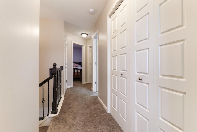 hall featuring carpet flooring, an upstairs landing, and baseboards