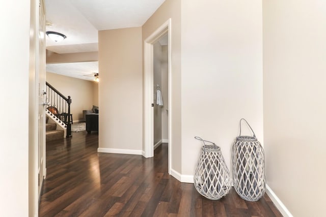 corridor with stairs, wood finished floors, and baseboards