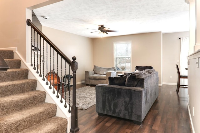 living room with a textured ceiling, ceiling fan, dark wood-type flooring, and baseboards