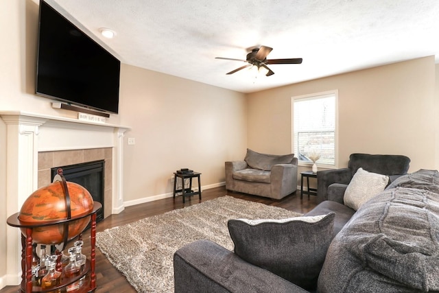 living area with a ceiling fan, baseboards, wood finished floors, and a tile fireplace