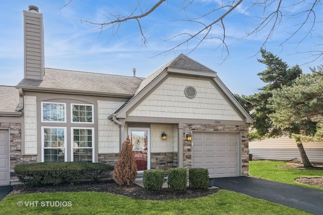 view of front of home with roof with shingles, an attached garage, a chimney, stone siding, and aphalt driveway