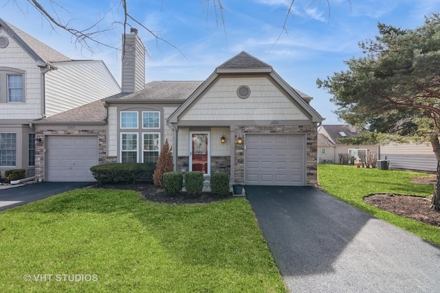 view of front of property with a front lawn, stone siding, a garage, and driveway