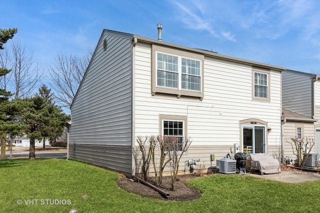 rear view of property featuring central AC unit and a lawn