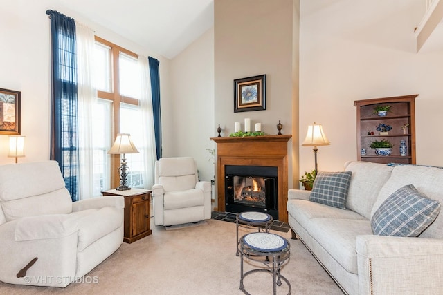 living room featuring light carpet, plenty of natural light, high vaulted ceiling, and a glass covered fireplace